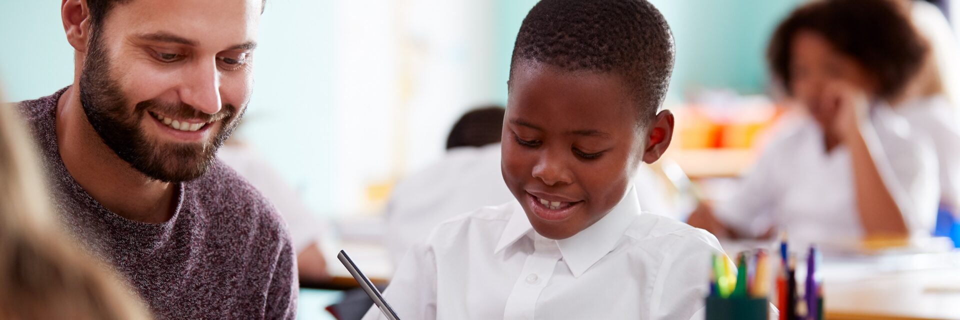 Male Teacher working with KS1 student in class