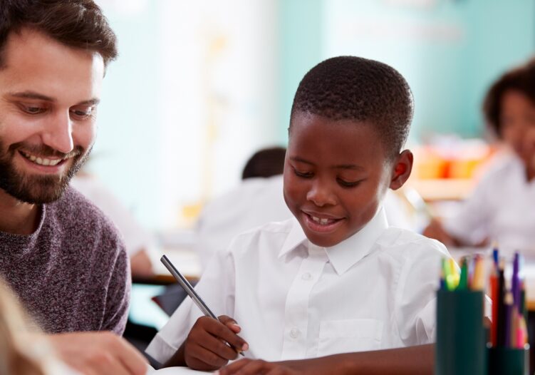 Male Teacher working with KS1 student in class
